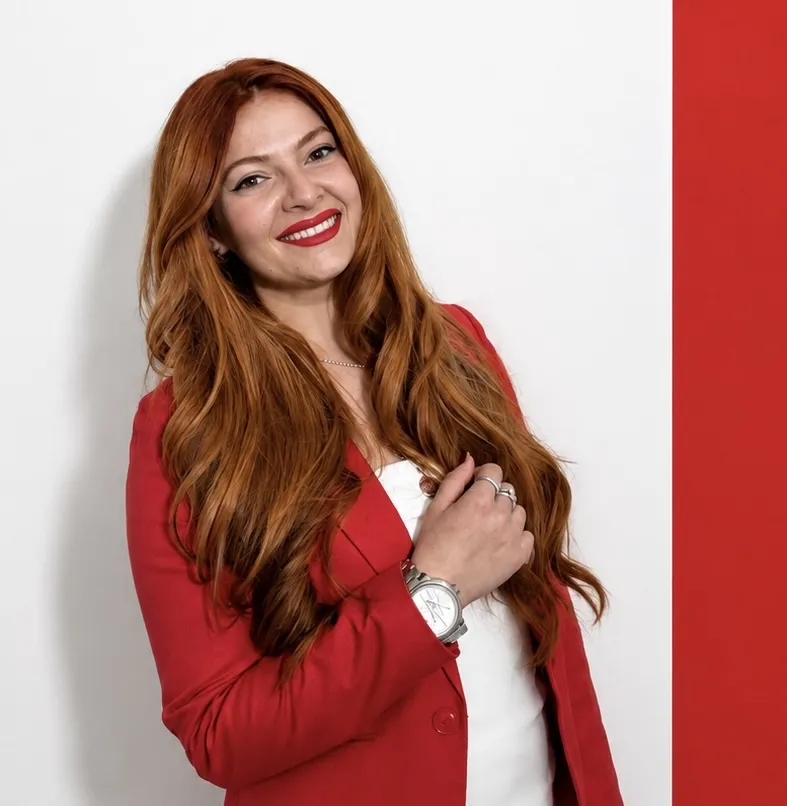 Oksana Nasadiuk, founder of OKSee Law, in a red jacket against a white wall